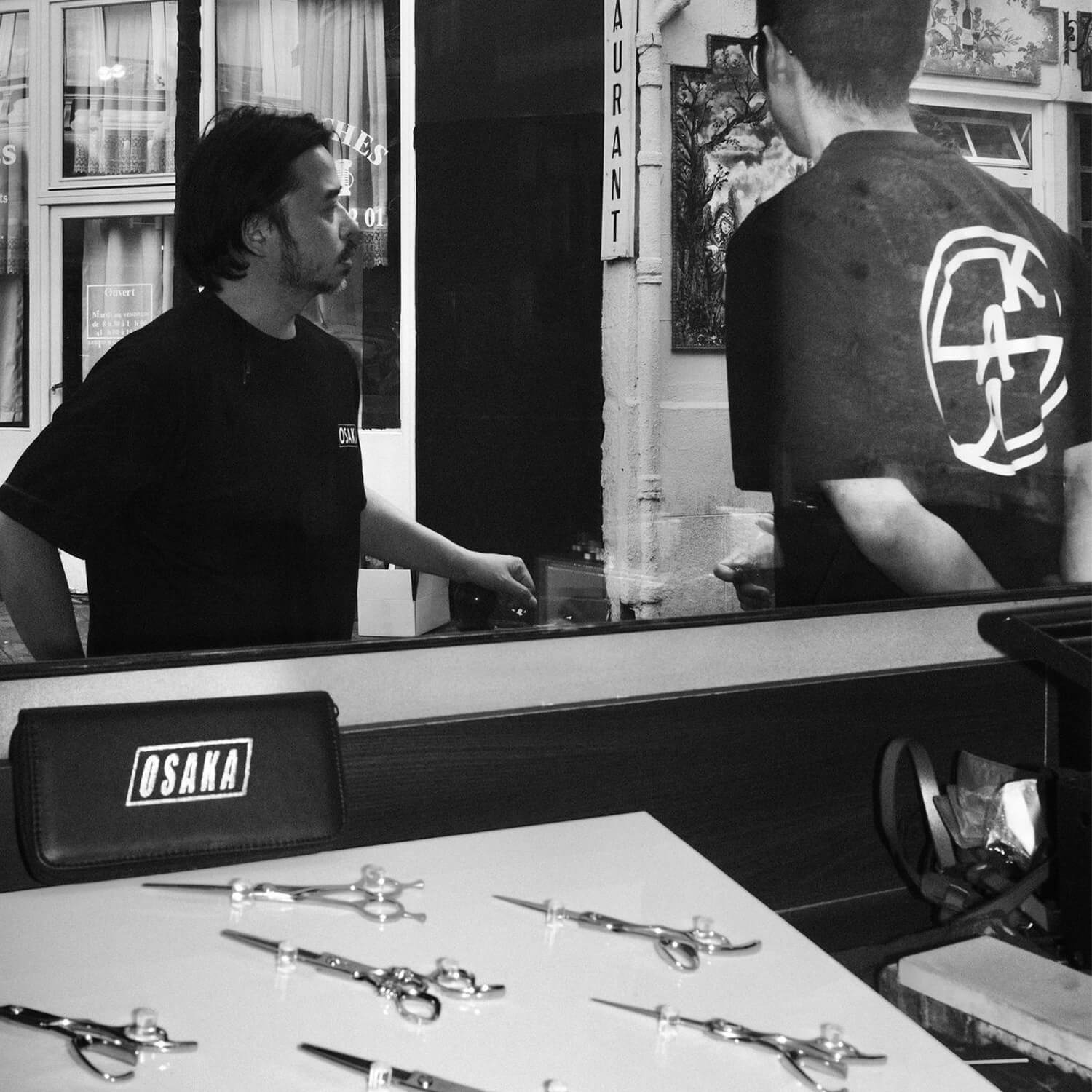 2 personnes portant le tshirt des ciseaux osaka. Ciseaux Osaka en avant plan.